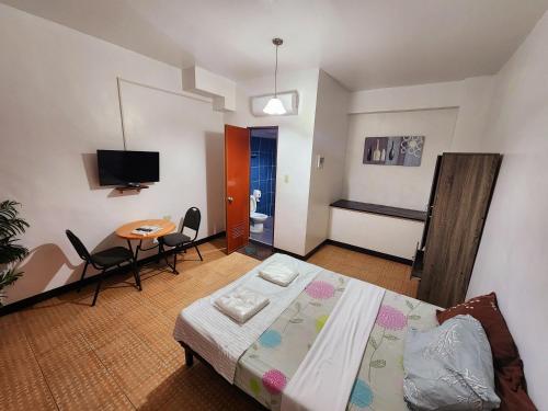 a bedroom with a bed and a table and chairs at MB's Garden Inn in Mactan
