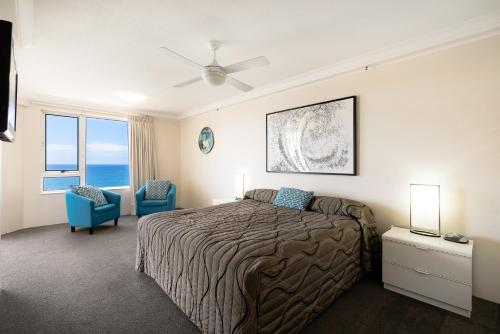 a bedroom with a bed and two blue chairs at Belle Maison Apartments - Official in Gold Coast