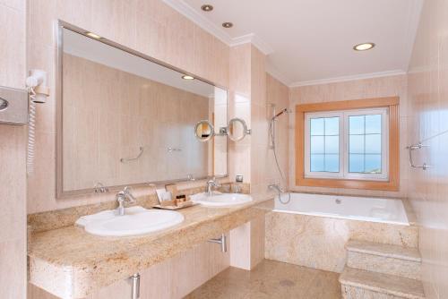 łazienka z 2 umywalkami, wanną i lustrem w obiekcie Talaso Atlántico w mieście Mougás