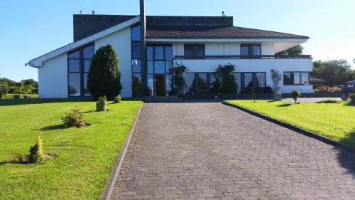 a large white house with a brick driveway at Hazelwood Country House in Adare
