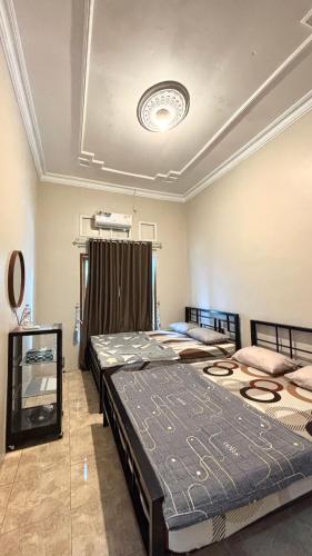 two twin beds in a room with a ceiling at HARMONI GUEST HOUSE tumpak sewu in Sumberbopong