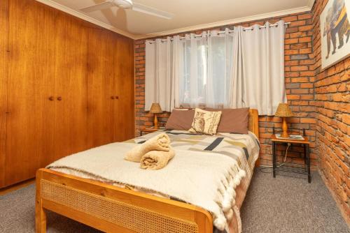 a teddy bear sitting on a bed in a bedroom at Bromeliads in Iluka