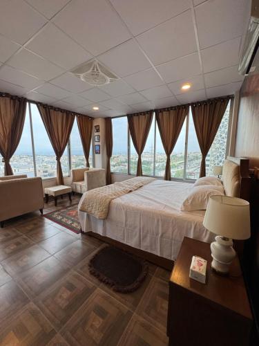 a bedroom with a large bed and large windows at Capresso Homes 4 in Islamabad