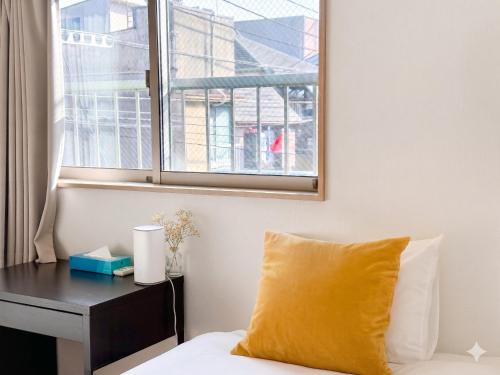 a bed with a yellow pillow next to a desk at KANAU in Tokyo