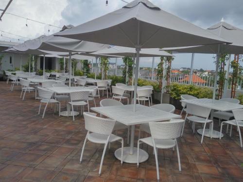 a row of white tables and chairs with umbrellas at Jambuluwuk Oceano Seminyak Hotel in Seminyak