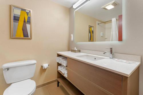 a bathroom with a toilet and a sink with a mirror at Comfort Suites Pittsburgh Airport in Coraopolis