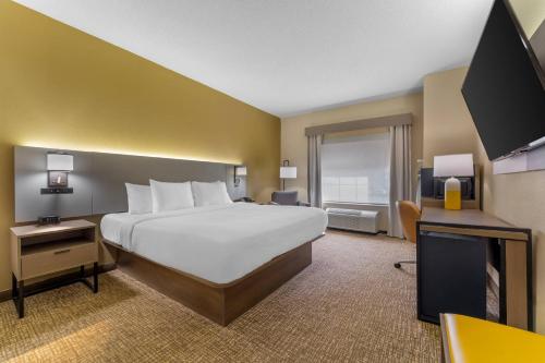 a hotel room with a large bed and a flat screen tv at Comfort Suites Pittsburgh Airport in Coraopolis