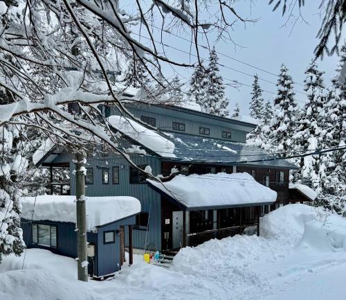 a house covered in snow with snow covered trees at Bears Den Mountain Lodge in Hakuba