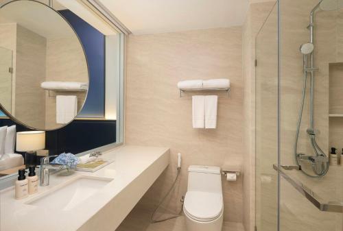 a bathroom with a toilet and a shower with a mirror at Amari Buriram United in Buriram