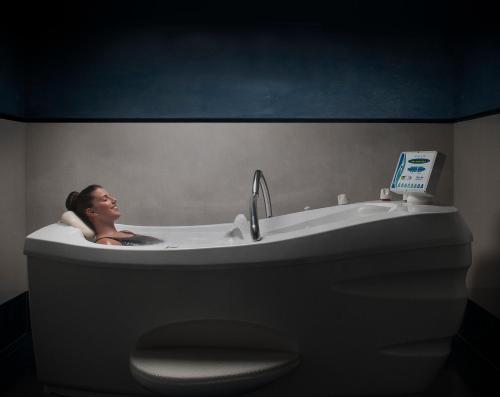 a woman sitting in a bath tub with a laptop at Talaso Atlántico in Mougás
