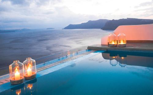 a swimming pool with candles in bottles on the water at Santorini Secret Suites & Spa, Small Luxury Hotels of the World in Oia