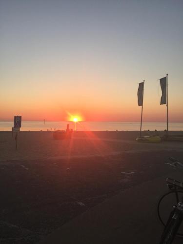 a sunset on the beach with flags in the sand at Bed & Breakfast Zeeland in Renesse