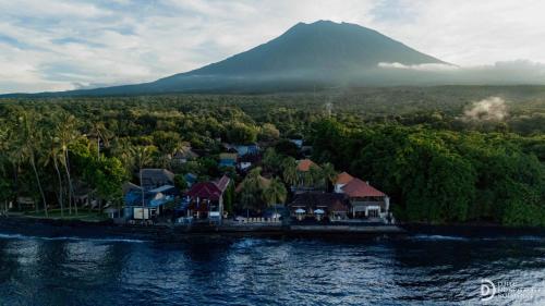 an island in the water with a mountain in the background at Paradise Palm Beach Bungalows and Dive Center in Tulamben