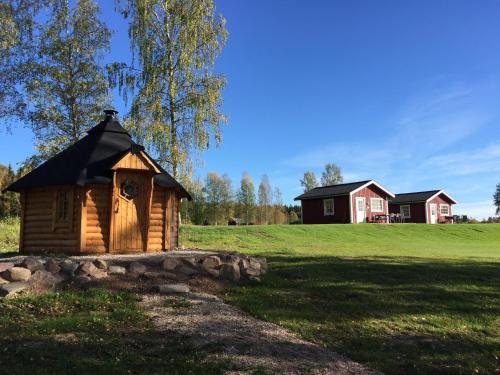 Sörmarks Camping في Sörmark: كابينة خشبية في حقل مع منزل في الخلفية