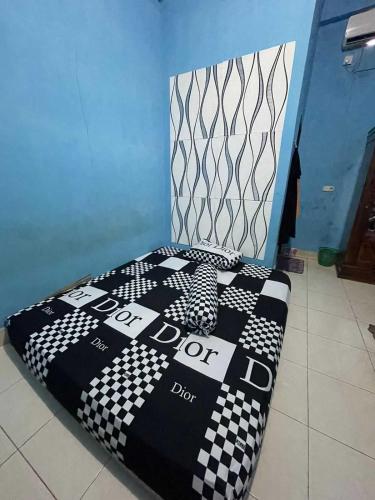a bed with a checkered blanket on top of it at EXPRESS O 91669 Kost Amel Near Taman Mattirotasi in Parepare