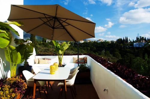 a table and chairs with an umbrella on a balcony at Botanic Home in Marbella