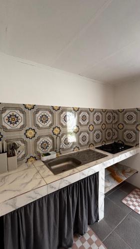 a kitchen with a sink and a tile wall at Anugerah's House in Katiet