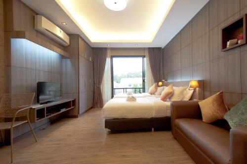 a bedroom with a bed and a couch and a television at Burapa Boutique in Chiang Mai
