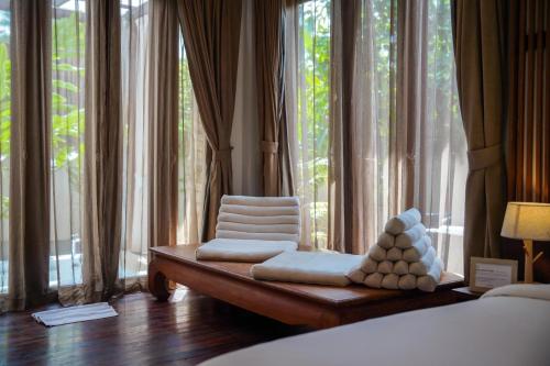 a bedroom with two chairs and large windows at Le Sen Boutique Hotel in Luang Prabang