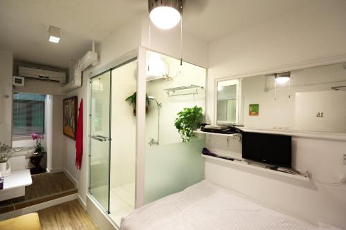a bathroom with a glass shower and a television at Apple lnn Causeway Bay in Hong Kong