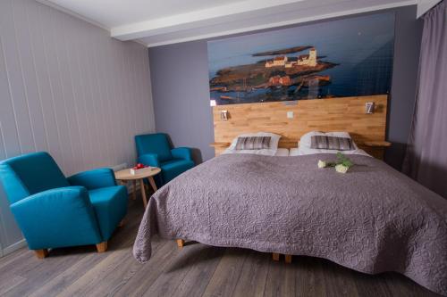 a bedroom with a bed and two blue chairs at Grimstad Vertshus in Grimstad