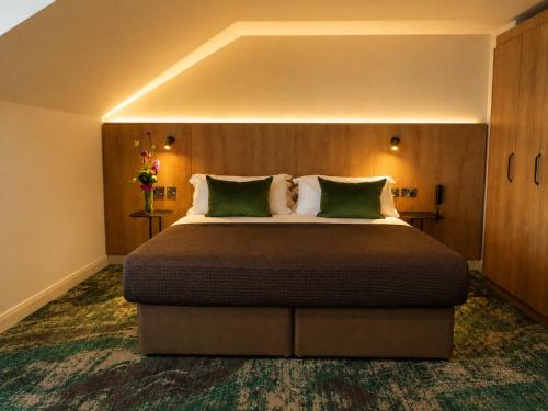 a bedroom with a large bed with green pillows at Springhill Hotel Kilkenny in Kilkenny