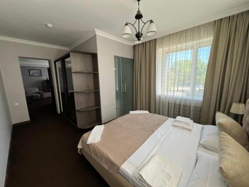 a bedroom with a large bed and a large window at Bereke Hotel in Shchūchīnsk