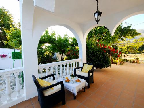 a porch with two chairs and a table with food on it at Cortijo El Búho - Casa rural con piscina privada en Montefrío in Montefrío