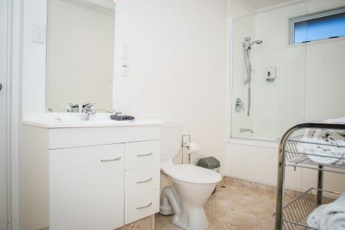 a white bathroom with a toilet and a sink at Edgewater Motel in Te Anau