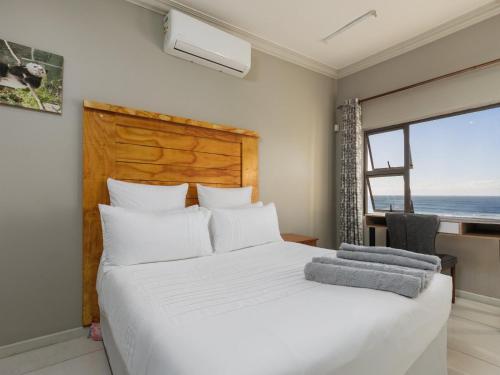 a bedroom with a white bed with a view of the ocean at La Vue in Port Shepstone