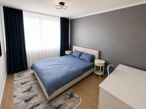 a bedroom with a bed with blue sheets and a window at NiC Apartment in Râmnicu Vâlcea