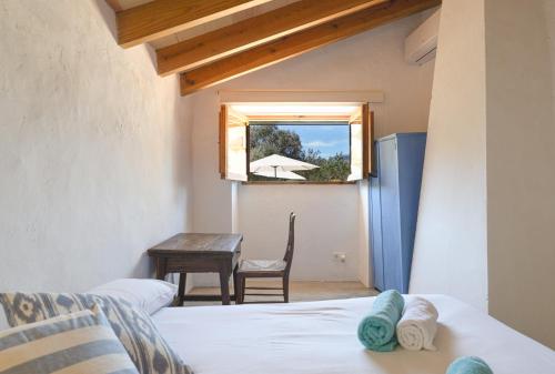 a room with a bed and a table and a window at Finca Es Coste by Rentallorca in Pollença