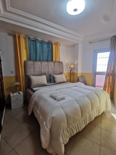 a large bedroom with a large bed with blue and yellow curtains at Studio VIP - Bonamoussadi - Groupe électrogène - 2douches in Douala