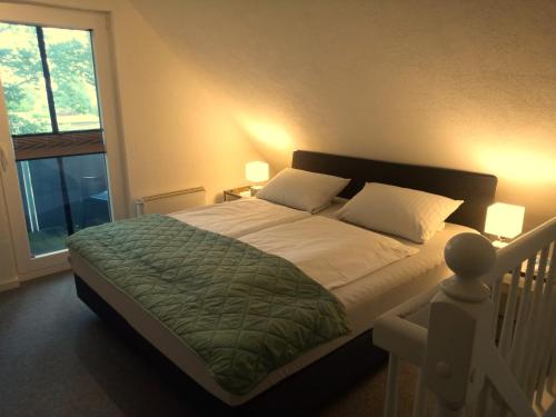 a bedroom with a large bed with white sheets and a window at Fischstübchen Neeberg Fewo 2 - Achterwasser in Krummin