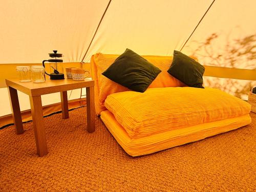 a room with a yellow chair and a table at Maesbury Meadows in Binegar