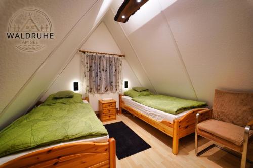 a bedroom with two beds and a chair in a attic at Waldruhe 37 inkl Bettwäsche und Handtücher, schlüsselloser Self-Check-in in Bad Arolsen