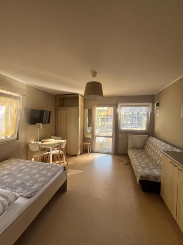 a bedroom with a bed and a couch and a table at Sosenkowo Domki Letniskowe in Pobierowo