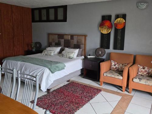 a bedroom with a bed and two chairs and a table at Witteberg in Krugersdorp