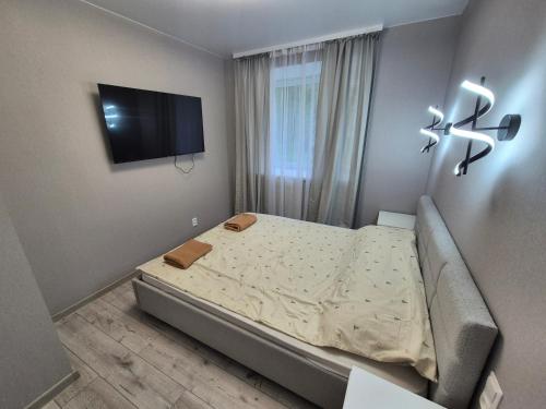 a small bedroom with a bed and a flat screen tv at 2-room apartment with separate rooms in Narva
