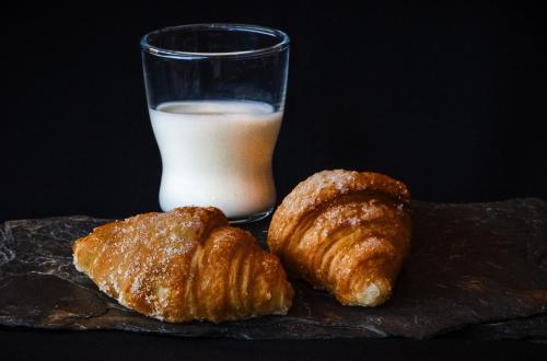 two croissants and a glass of milk on a table at Domus Fontis in Rome