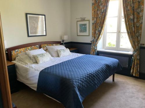 a bedroom with a bed with a blue blanket and a window at La Grange Terrou in Saint-Germain-de-Confolens