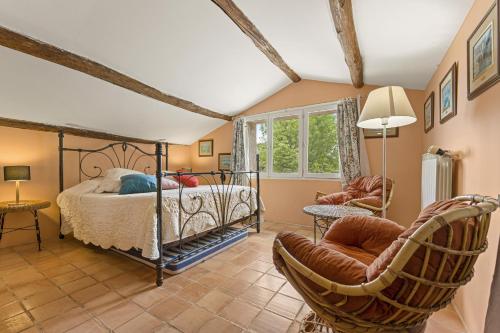 a bedroom with a bed and chairs in a room at Mas Abicou in Vézénobres