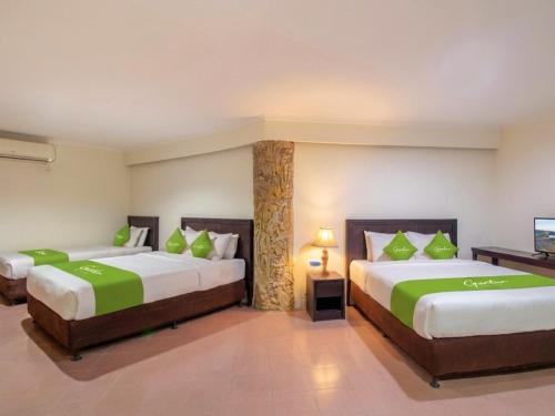 a bedroom with two beds with green pillows at Guntur Hotel Bali in Ketewel