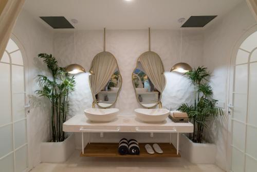 a bathroom with two sinks and two mirrors at Makyra by Bohemian Jogja Villas in Kejayan
