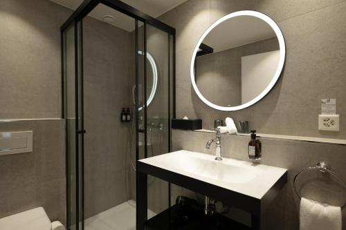 a bathroom with a sink and a shower with a mirror at Hotel Des Alpes in Lucerne