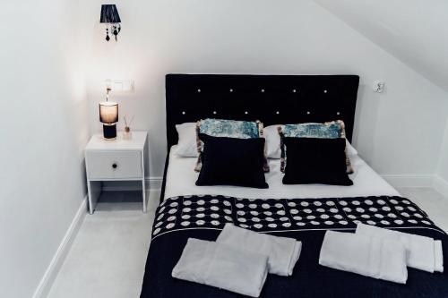 a large bed with black and white sheets and pillows at Willa Piryt - Kryształowe Wille Krynica Morska in Krynica Morska