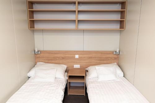 two beds in a small room with white sheets at Igal Thermal Camping in Igal