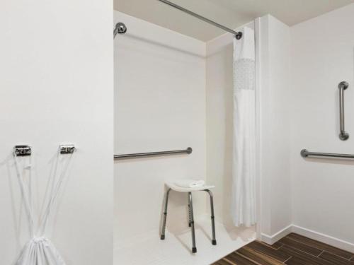 a white bathroom with a shower and a stool at Hampton Inn Bartow in Bartow