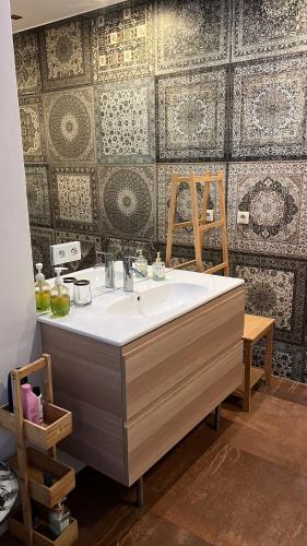 a bathroom with a large sink and a patterned wall at Rynek 5 Winiarnia in Lublin