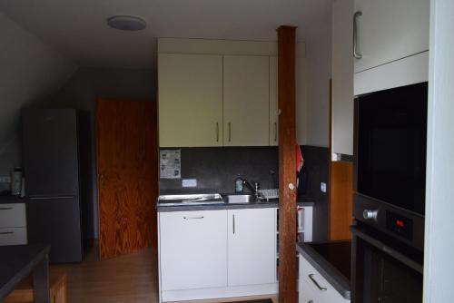 a kitchen with white cabinets and a black refrigerator at FeWo Vobbe in Dänischenhagen